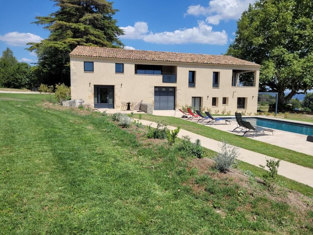 A two-story house with a swimming pool, a covered patio, and a well-maintained lawn.
