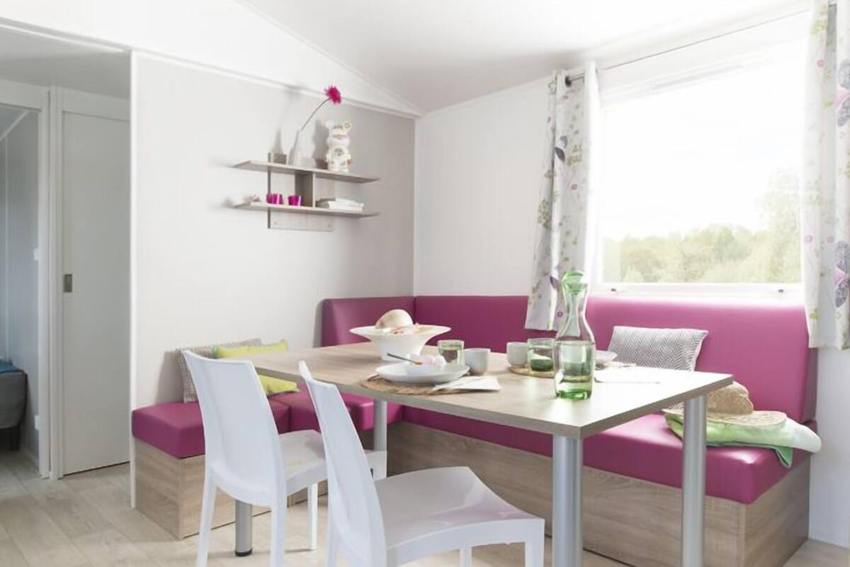 A modern room with a dining area, a bed, and a kitchenette.