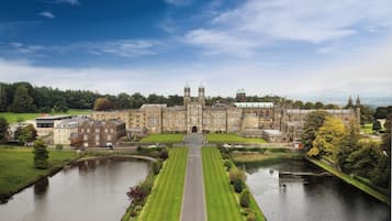 A large, historic building with a symmetrical facade, a central entrance, and a surrounding moat.