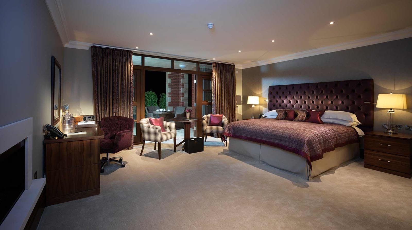 Ein Hotelzimmer mit einem großen Bett, einem Schreibtisch, einem Stuhl, einer Couch und einem Fenster mit Vorhängen.