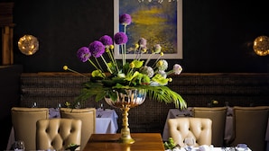 Una mesa de comedor con un centro de mesa floral, sillas tapizadas y un candelabro.