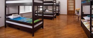A room with bunk beds, wooden flooring, a window with blinds, and a door with a frosted glass panel.