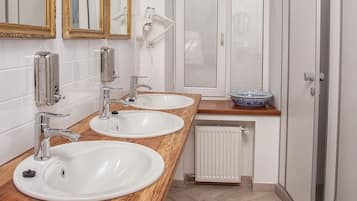 A modern bathroom with two sinks, a mirror, and a radiator.