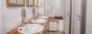 A modern bathroom with two sinks, a mirror, and a radiator.