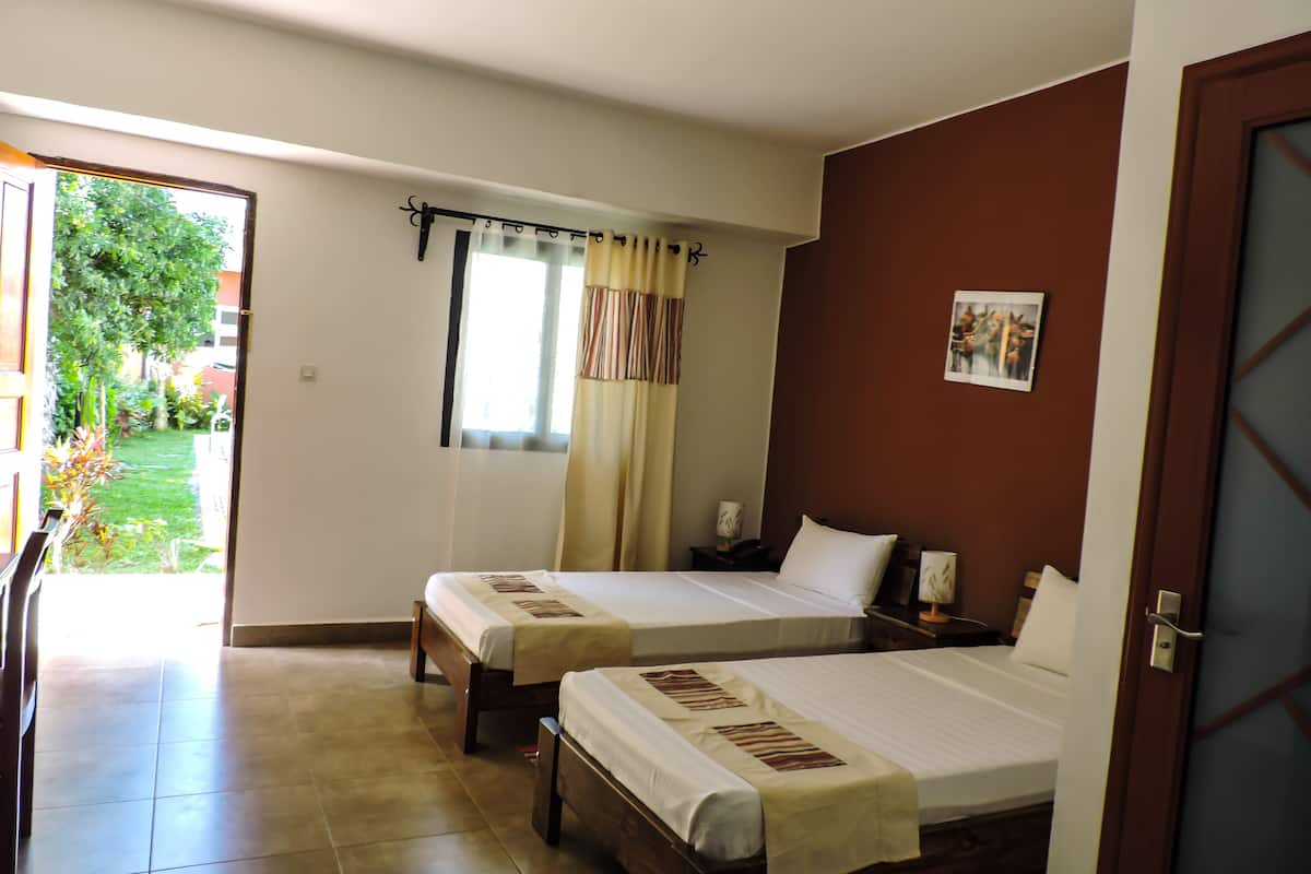 Une chambre d’hôtel avec deux lits, une salle de bain et une vue sur un jardin.