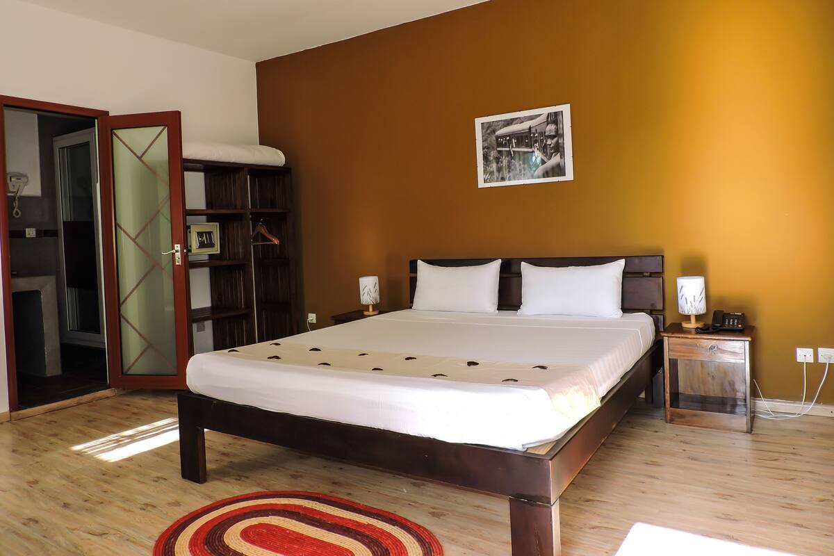 Une chambre à coucher comprenant un lit, des tables de chevet, une armoire et un tableau accroché au mur.