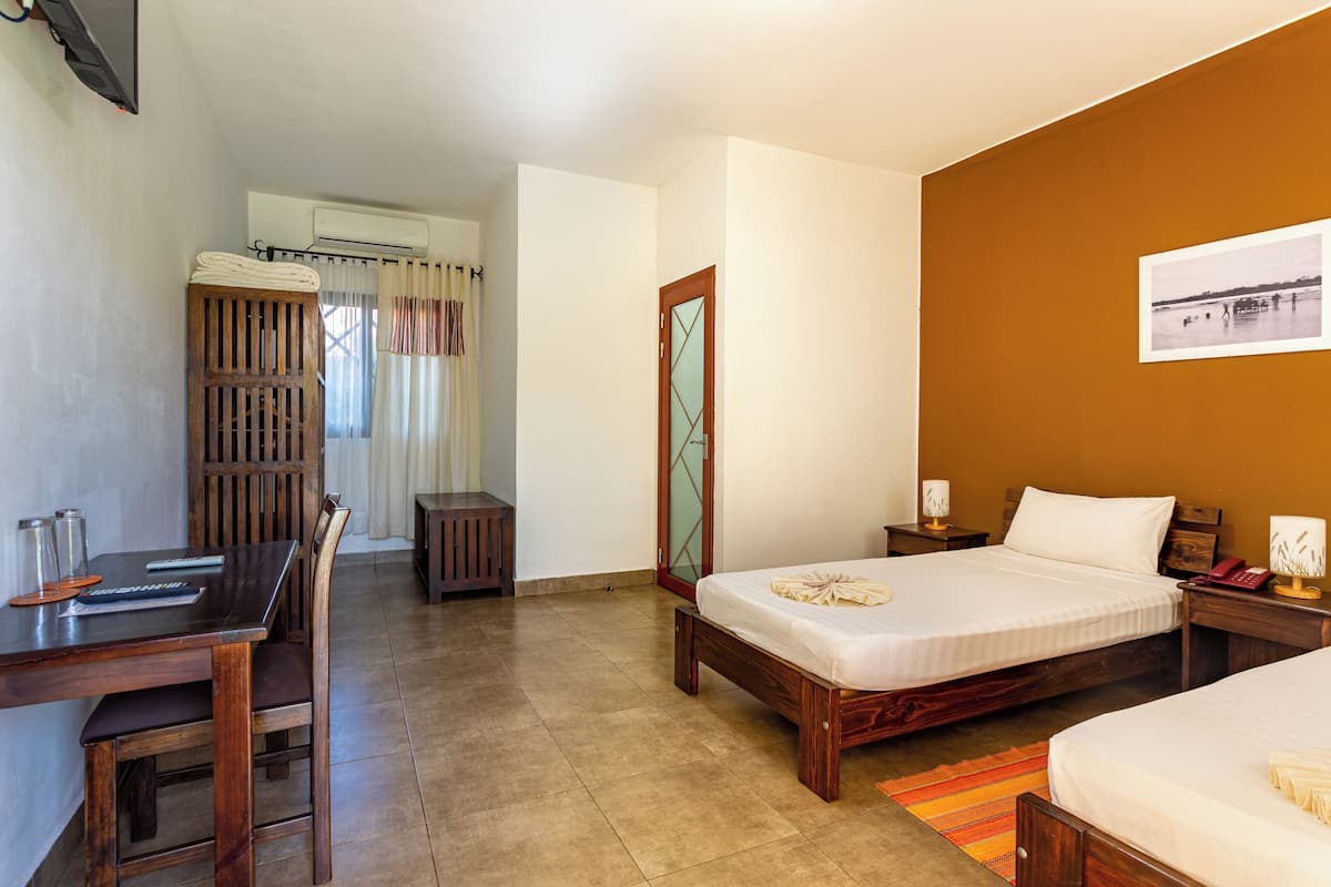 Une chambre d’hôtel comprenant un lit, une table de chevet et un bureau avec une chaise.