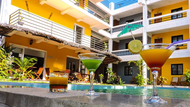A poolside area with two cocktails, a pool, and a building with balconies and outdoor seating. - Hotel H1 Manakara SCHM (Manakara)
