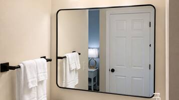 A bathroom with a white sink, black faucet, and a mirror with three lights.