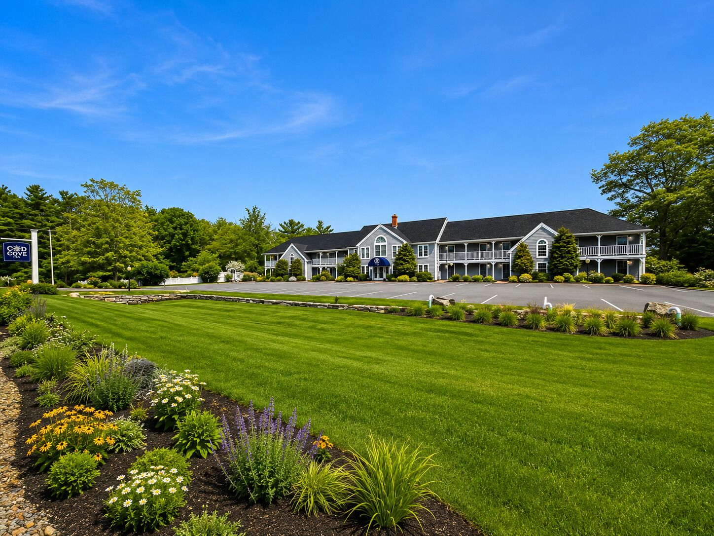 A hotel with a large lawn, a parking lot, and a sign indicating it is a C&D Cove hotel.