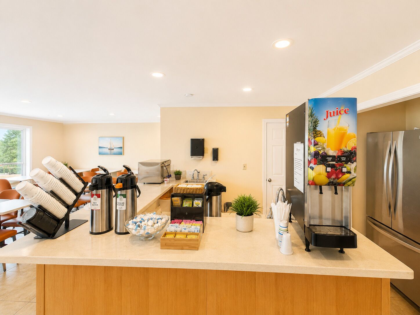 Un coin cuisine équipé d’un réfrigérateur, d’un distributeur de jus, d’un espace pour préparer le café et d’un bar pour prendre le petit-déjeuner.