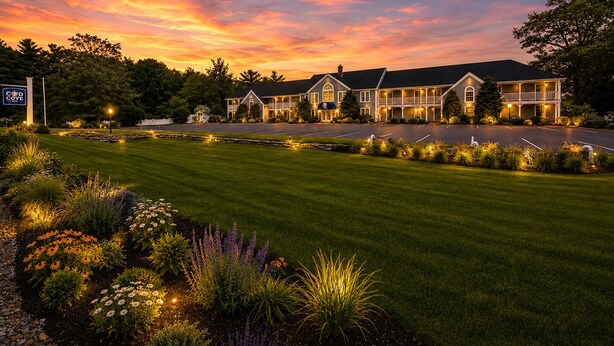 A hotel with a large driveway, well-maintained lawn, and a sign indicating the name. - Cod Cove Inn, BW Signature Collection (Edgecomb)