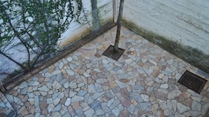A stone-tiled floor with a tree and a drain in a corner.