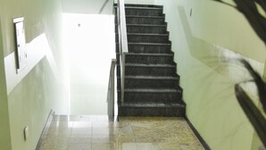 A staircase leading to an upper floor, with a tiled floor and a plant in the foreground.