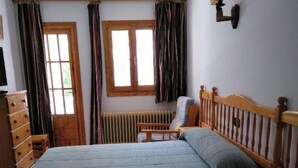 Un dormitorio con una cama grande, muebles de madera, un radiador y cortinas.