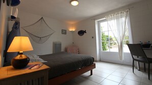 Quarto com cama, luminária de cabeceira e janela com cortinas.
