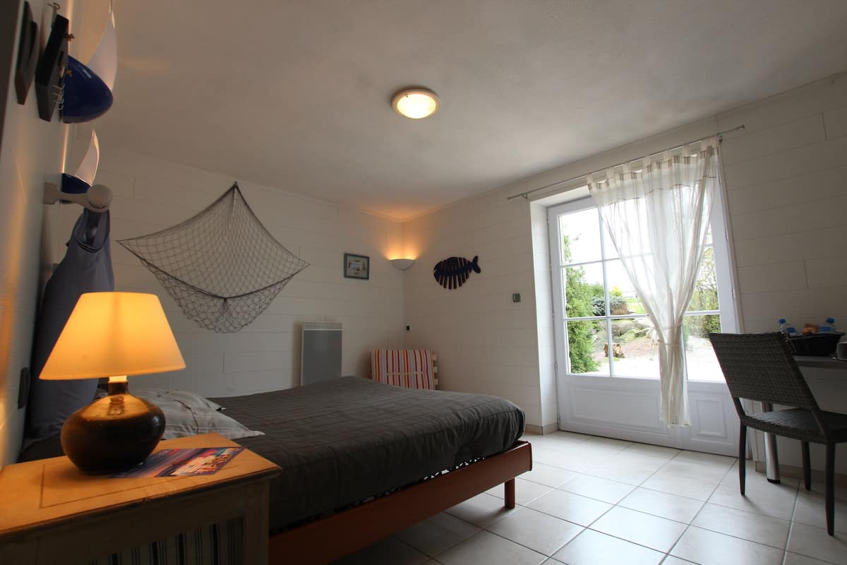 Ein Schlafzimmer mit einem Bett, einer Nachttischlampe und einem Fenster mit Vorhängen.