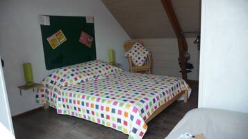 A bedroom with a bed, a chair, a green bulletin board, and a wooden ceiling.