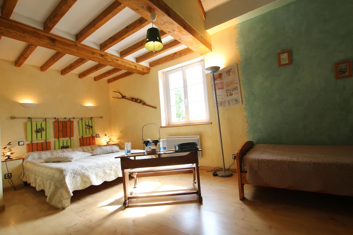 Ein Schlafzimmer mit Bett, Schreibtisch, Lampe und Fenster.
