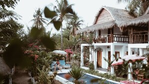 A resort with a pool, lounge chairs, and a thatched-roof building. - El Jardin de Shambala (Gili Air)