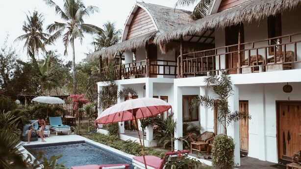 A resort with a pool, lounge chairs, and thatched-roof structures. - El Jardin de Shambala (Gili Air)