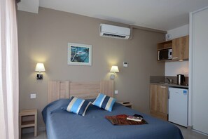 Une chambre d’hôtel équipée d’un lit, de lampes de chevet, d’un tableau, d’une petite table, d’un four à micro-ondes et d’un réfrigérateur.