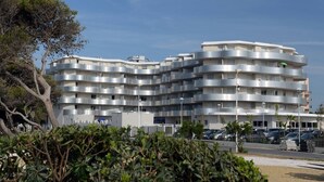 A multi-story residential building with balconies, a parking area, and surrounding vegetation. - Relaxing Stay Near the Sea (Le Barcares)