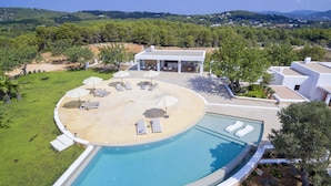 A modern pool area with lounge chairs and umbrellas, surrounded by a landscaped garden and a view of the countryside. - Agroturismo Can Toni Xumeu - Only Adults (Santa Eulalia del Rio)