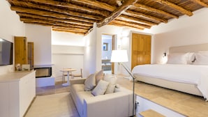 A modern hotel room with a wooden ceiling, a bed, a sofa, a desk, and a lamp. - Agroturismo Can Toni Xumeu - Only Adults (Santa Eulalia del Rio)