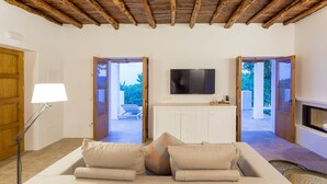 A modern living room with a wooden ceiling, a flat-screen TV, a sofa with cushions, and a lamp. - Agroturismo Can Toni Xumeu - Only Adults (Santa Eulalia del Rio)