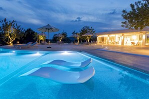 A swimming pool with lounge chairs and umbrellas, surrounded by trees and a building with outdoor seating. - Agroturismo Can Toni Xumeu - Only Adults (Santa Eulalia del Rio)