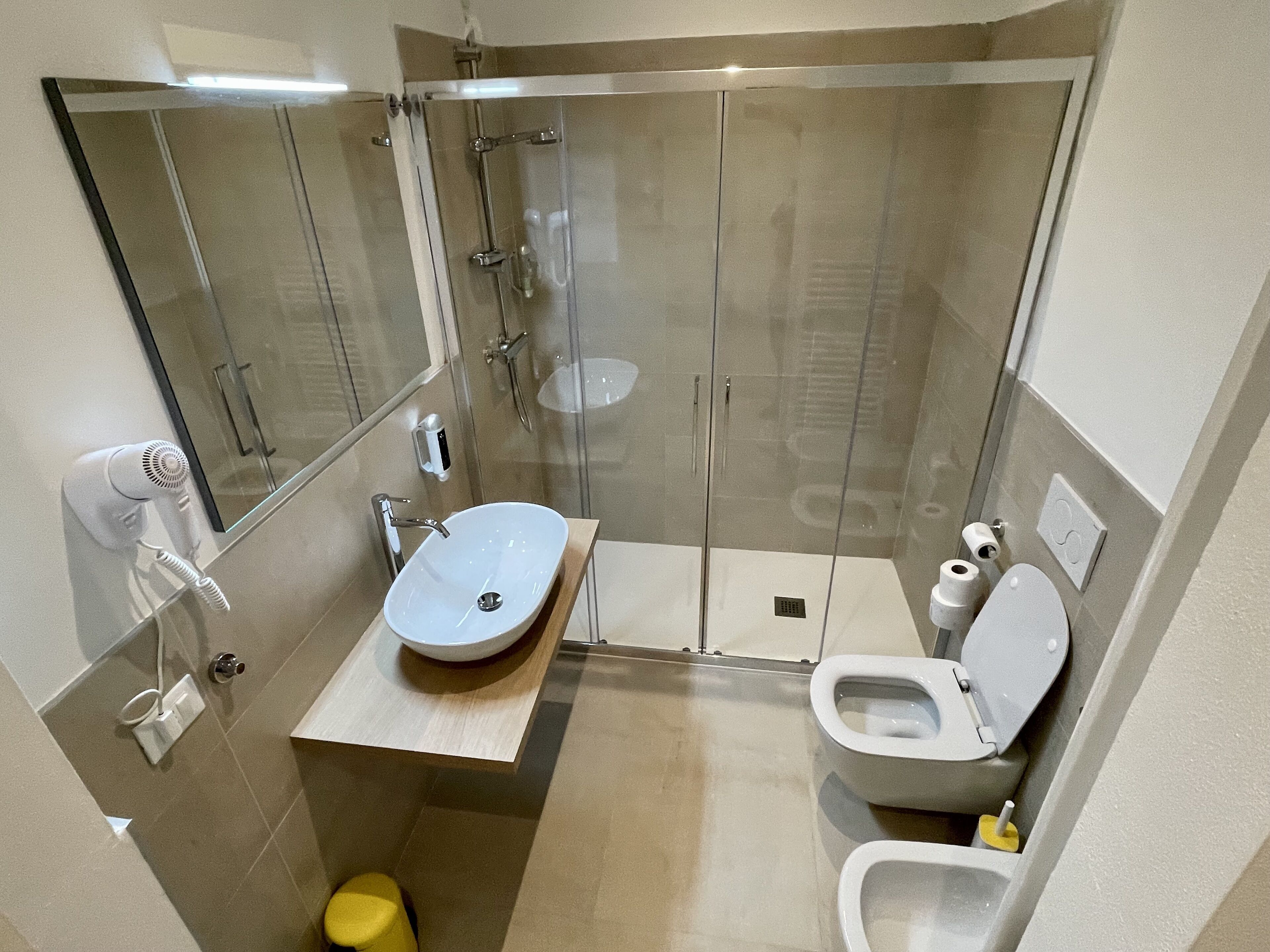 A modern bathroom with a glass-enclosed shower, a white sink, and a toilet.