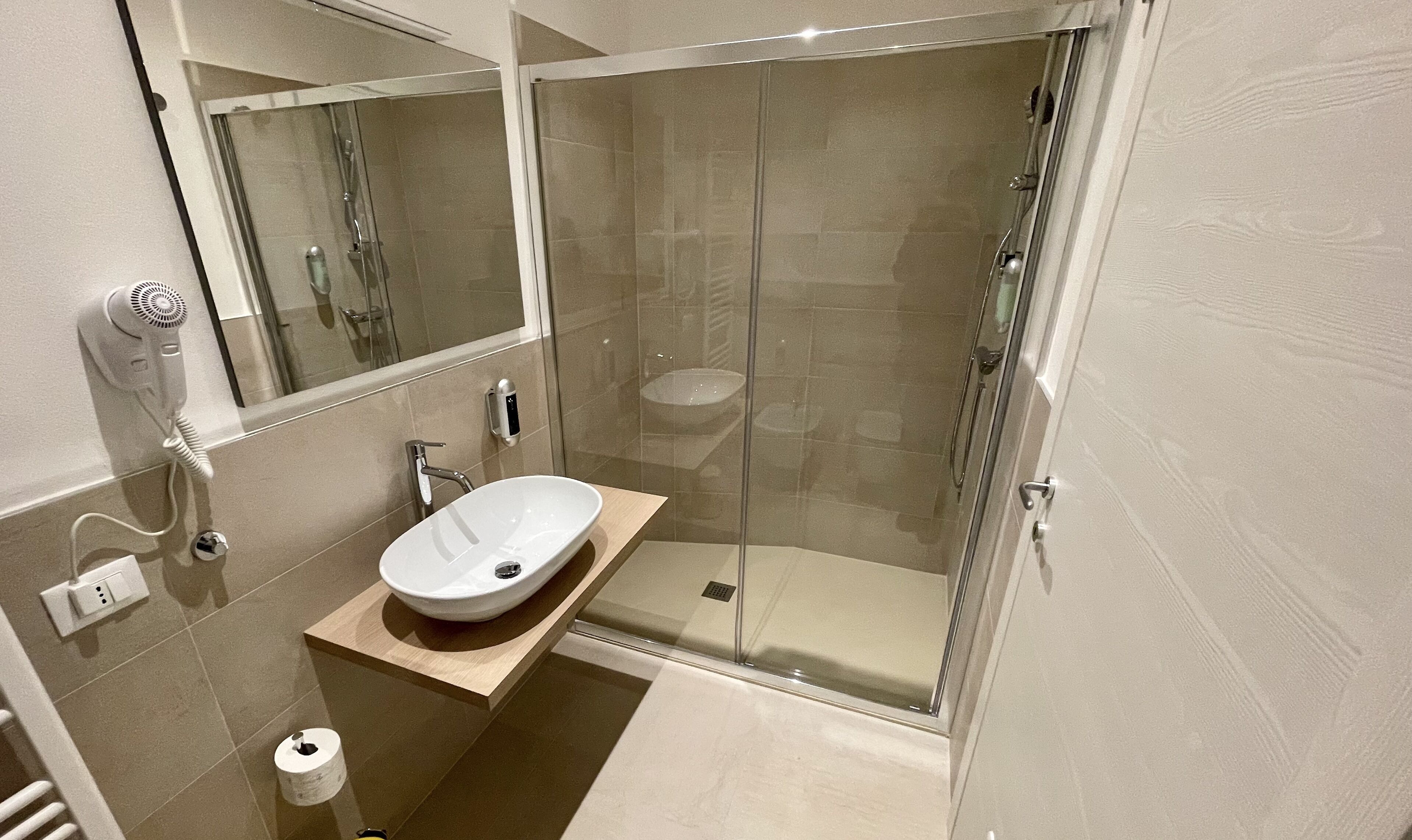 A modern bathroom with a glass-enclosed shower, a white sink, and a mirror.