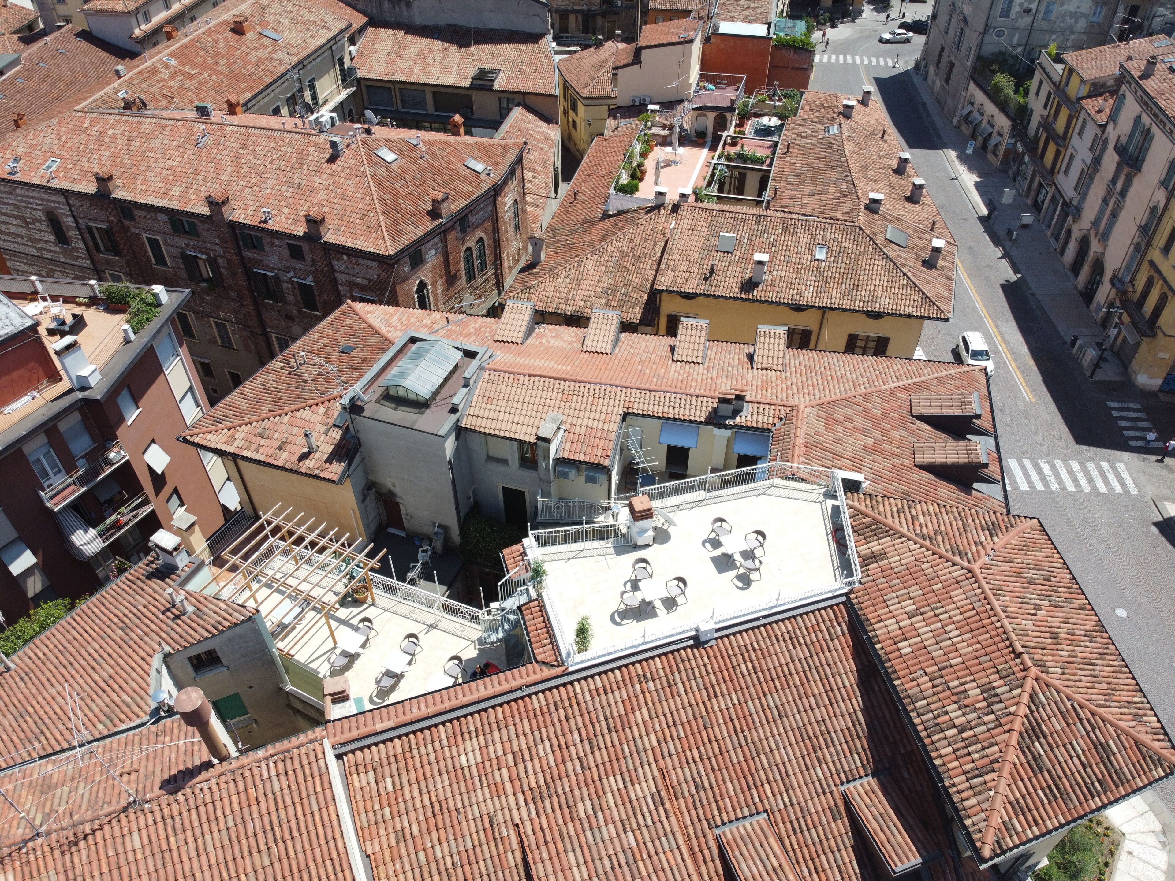 A high-angle view of a densely packed urban area with terracotta-tiled rooftops, some with flat roofs and others with sloped roofs.
