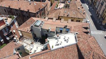 A high-angle view of a densely packed urban area with terracotta-tiled rooftops, some with flat roofs and others with sloped roofs.