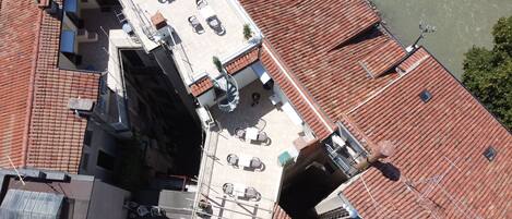 Terraço no topo do prédio com várias áreas de estar, uma escada em espiral e vista para o rio.