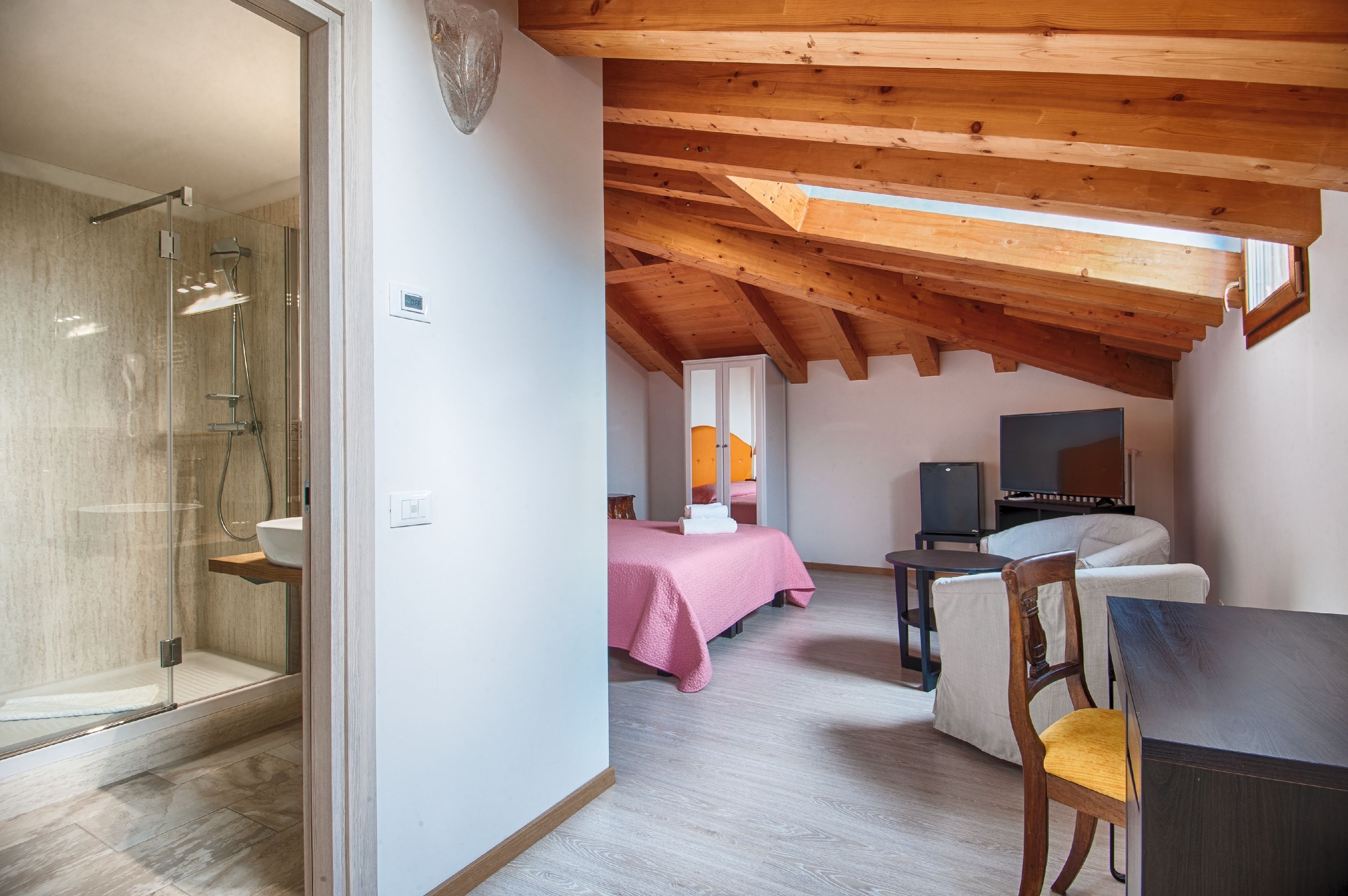 Un dormitorio con cama, televisor y techo de madera.