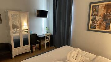 Een hotelkamer met een bed, een bureau, een stoel, een kledingkast, een televisie en een schilderij aan de muur.
