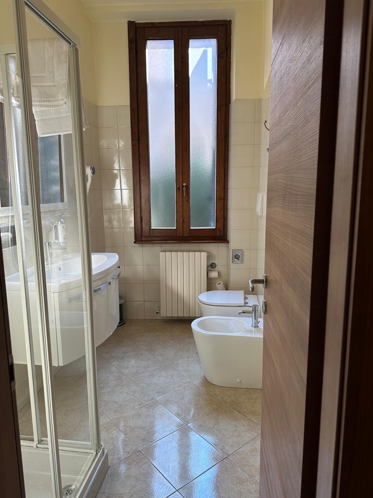 A bathroom with a shower, toilet, and bidet.
