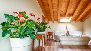 A cozy living room with a wooden ceiling, a white sofa, and large potted plants. - Lady Verona (Verona)