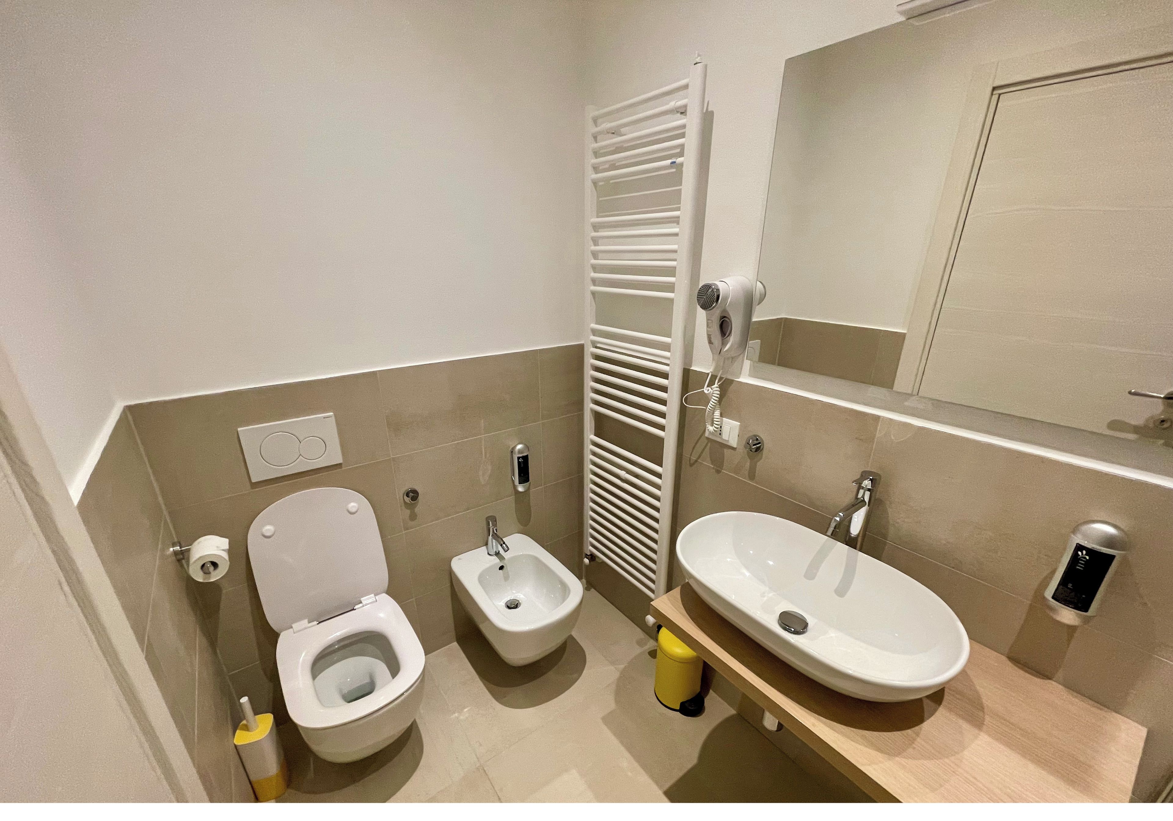 Une salle de bain comprenant des toilettes, un bidet, un lavabo et un porte-serviettes.