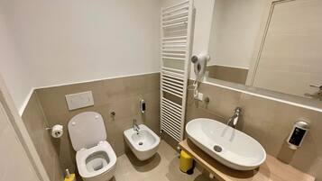 Une salle de bain comprenant des toilettes, un bidet, un lavabo et un porte-serviettes.