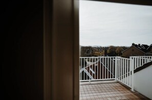 A balcony with a white railing overlooking a residential area with houses and a mountain in the distance. - De Zilte Melis (Meliskerke)