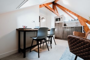 A compact kitchen with modern appliances, a dining area with two chairs, and a wooden ceiling beam. - De Zilte Melis (Meliskerke)
