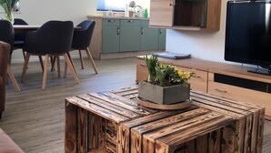 Un salon moderne avec une table basse en bois, un téléviseur et un coin repas comprenant des chaises et une table.
