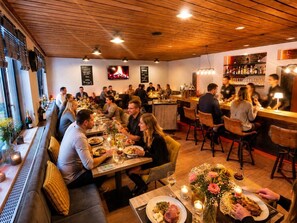 Un restaurante con techo de madera, mesas con velas y una zona de bar.