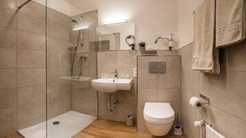 Ein modernes Badezimmer mit Duschkabine aus Glas, Waschbecken, Toilette und Handtuchhalter.