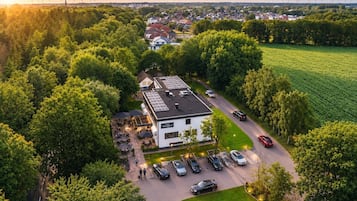 An aerial view of a hotel with a parking lot, surrounded by trees and a field.