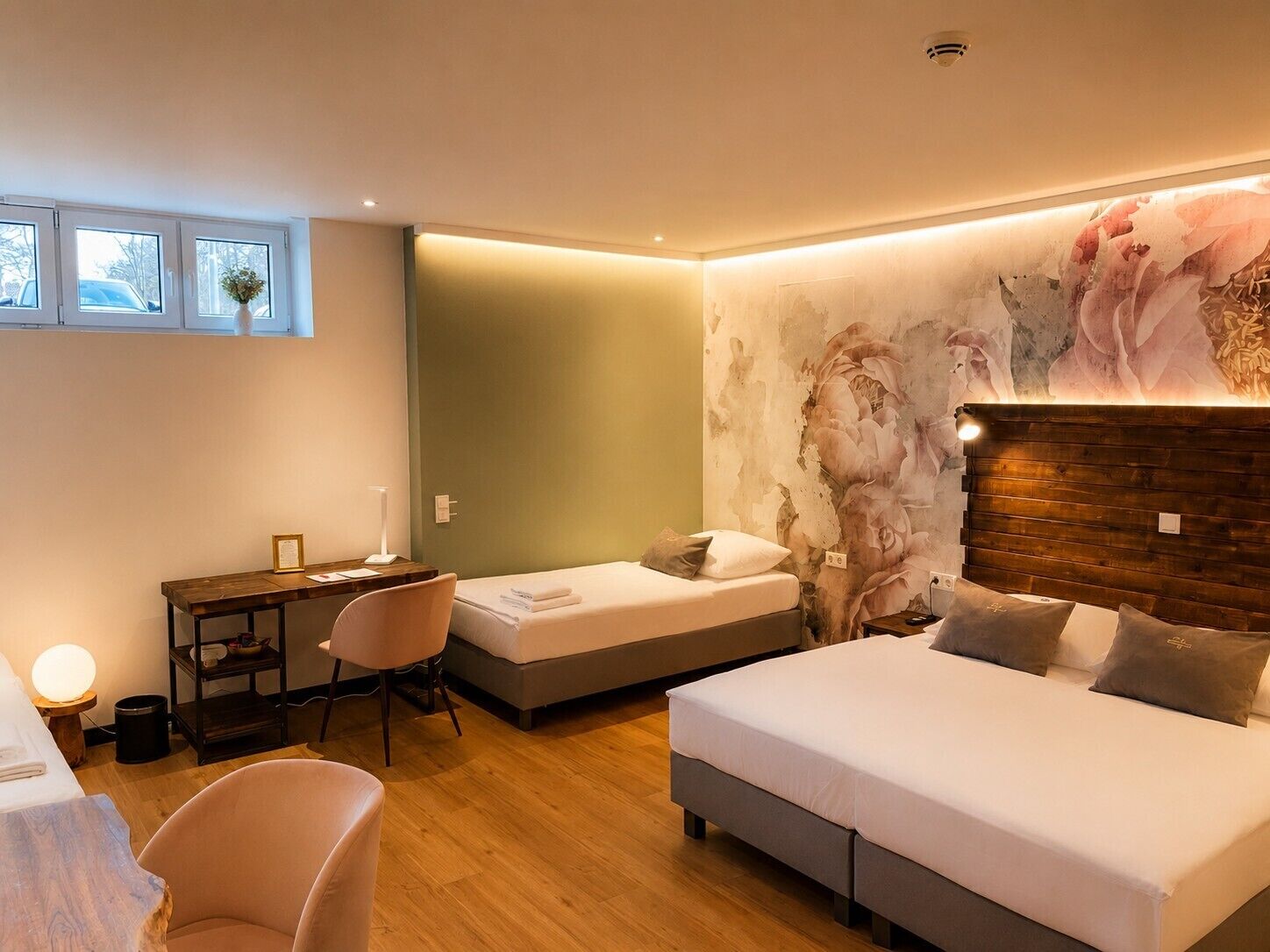 Een slaapkamer met een bed, bureau, stoel en wand met een bloemenmural.