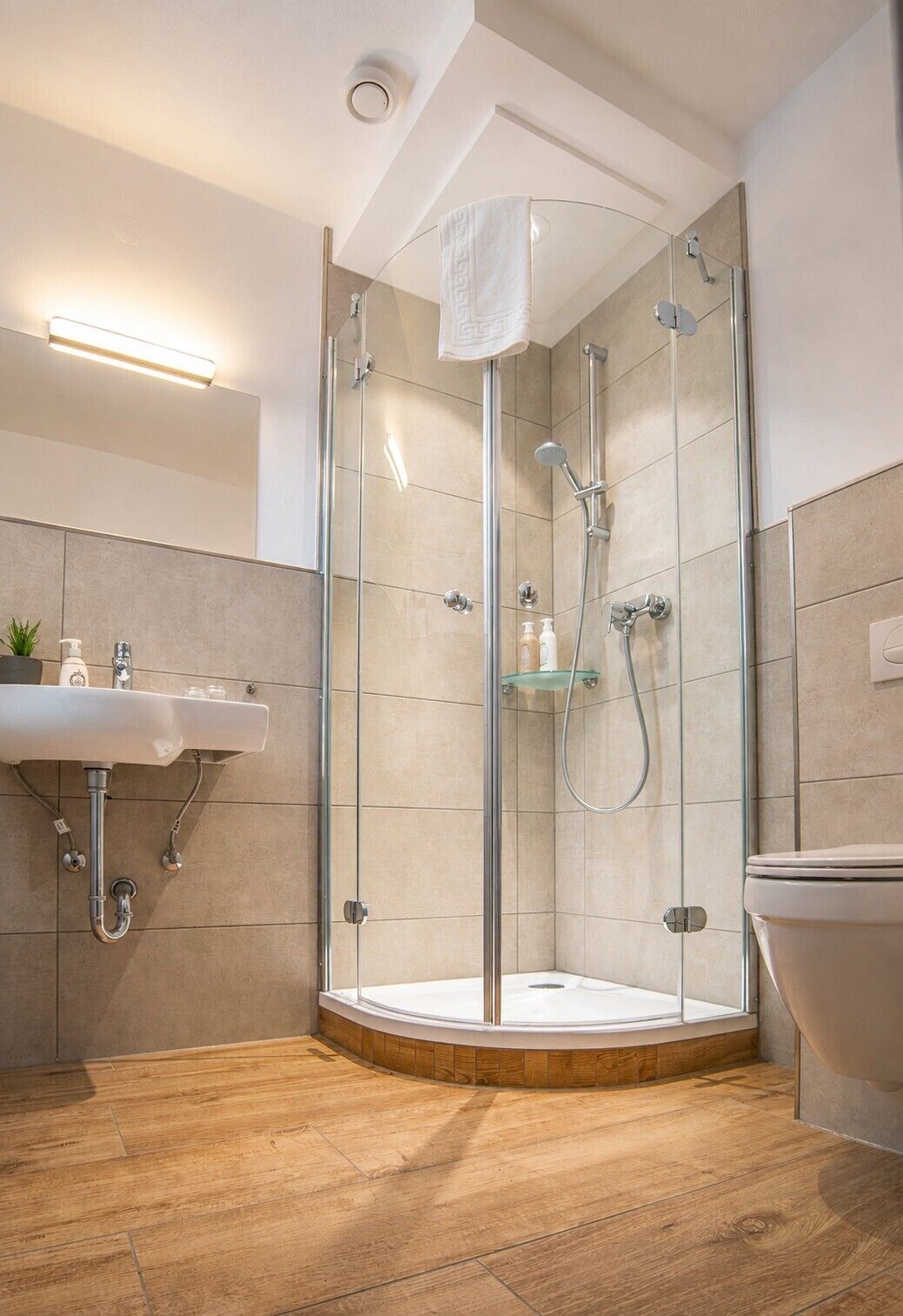 A modern bathroom with a glass-enclosed shower, a sink, and a toilet.